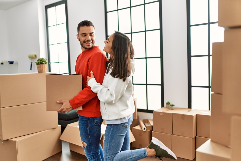 Young latin couple smiling happy holding cardboard box at new home.Winter moving.