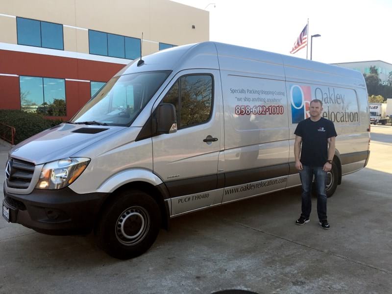 a man standing next to a Oakley Relocation branded silver van