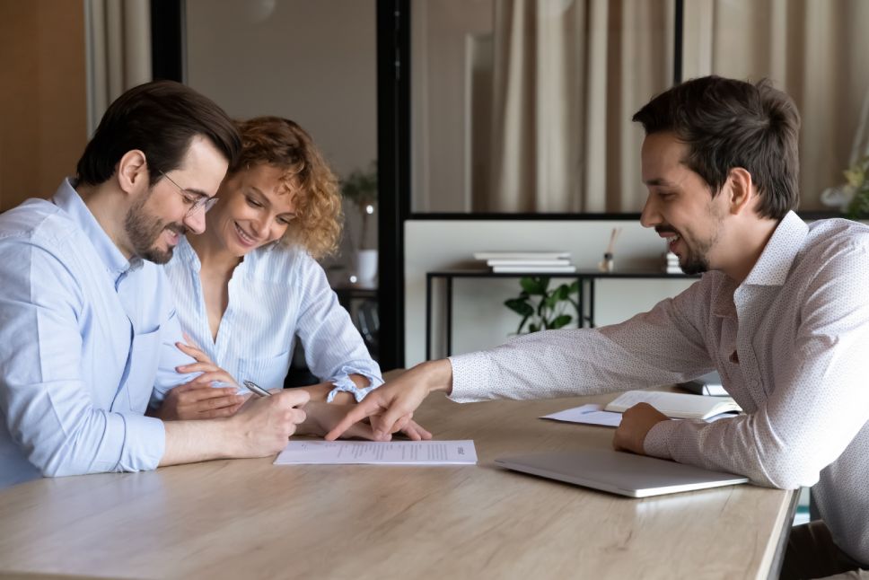 Happy couple of clients signing house buying, rent contract, insurance agreement, filling bank papers for mortgage, loan, meeting with lawyer, broker, realtor, real estate agent in office