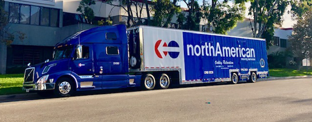 a blue semi NorthAmerican Van lines truck, parked in front of a building