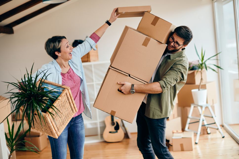 Happy couple having fun with carboard boxes while moving into new home.