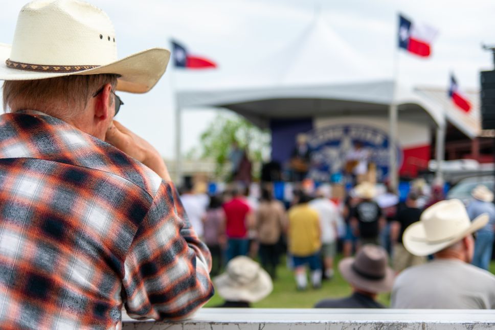 A spectator watches as Junior Brown and his band perform at a vintage car show near Austin, TX.