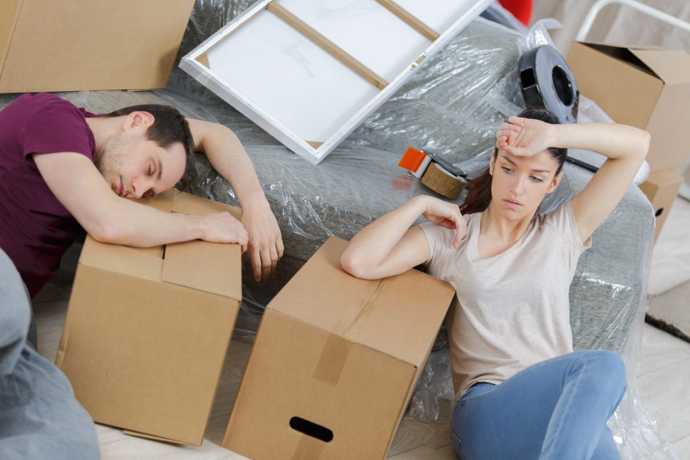 tired couple resting in new home during moving