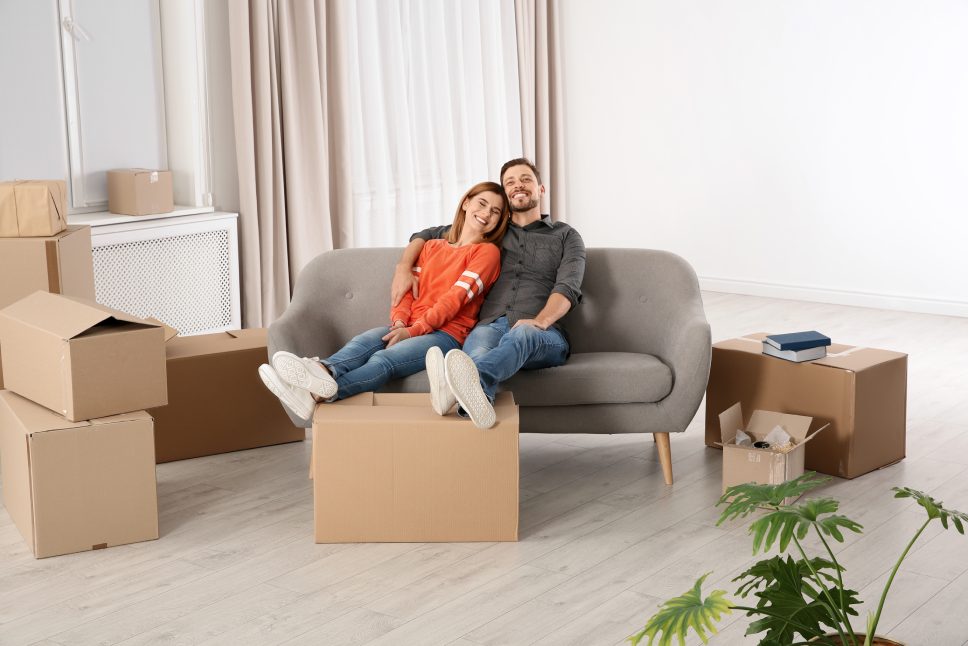 Couple resting on sofa near moving boxes in their new house