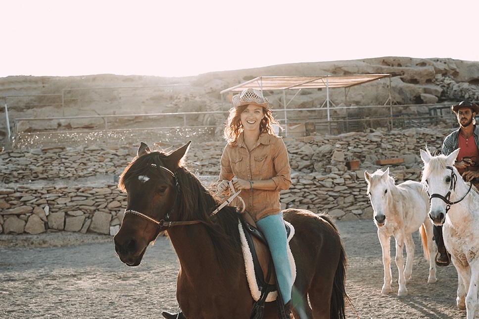 a lady riding a horse wearing a cowboy hat