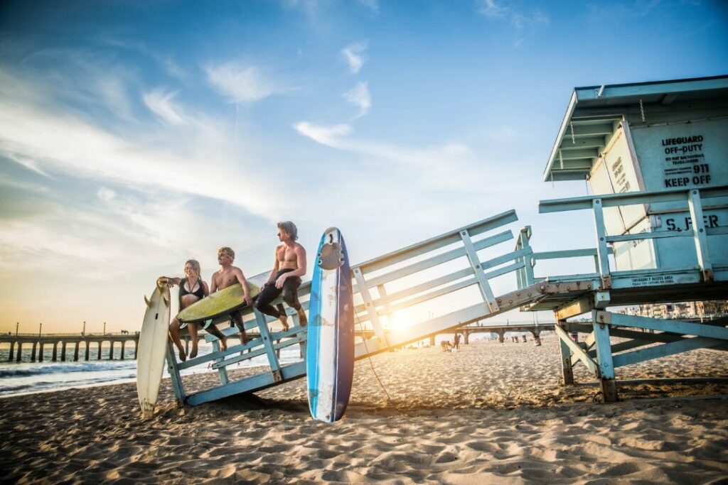 Group of friends going to surf at the beach - Young adults bonding at the beach