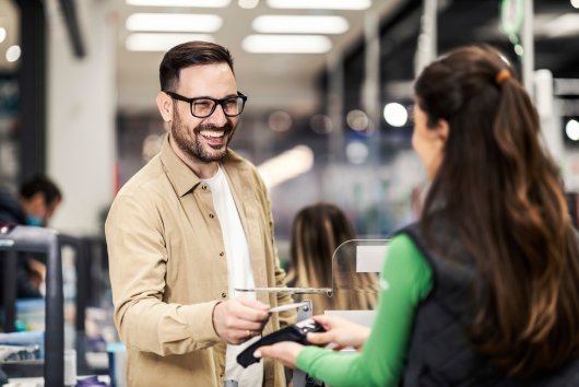 A smiling customer using credit card in supermarket at checkout.