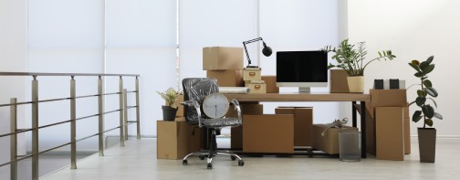 Cardboard boxes, computer and furniture in new office. Moving day