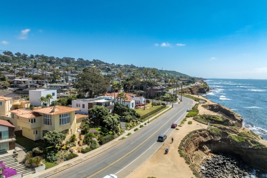 Aerial view of hillside luxury single family homes above Sunset Beach San Diego with palm trees and large terrace