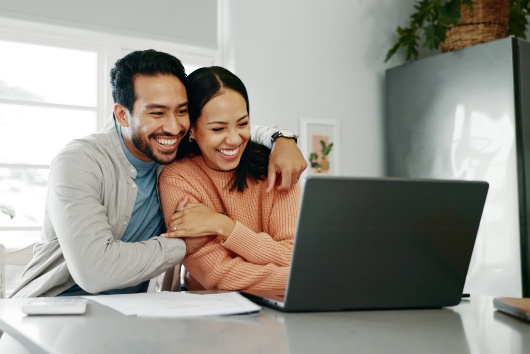 Happy couple, paperwork and hug with laptop for budget, paying bills or estate planning. Married people, embrace and documents for insurance policy, investing and savings in apartment or family home