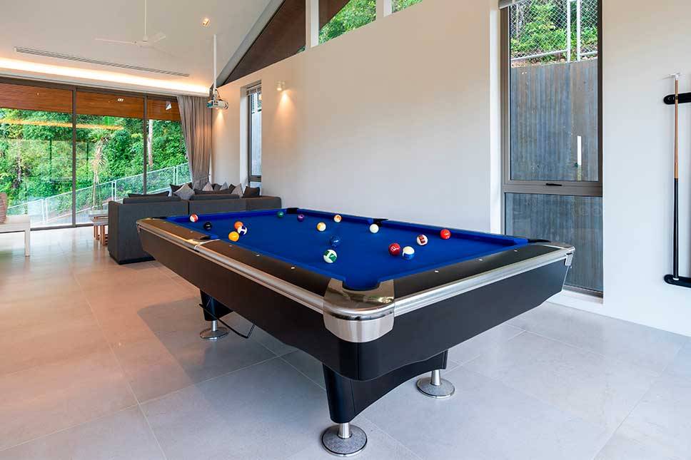 A modern home interior featuring a pool table, couch, and sliding glass door, highlighting a recreational space.
