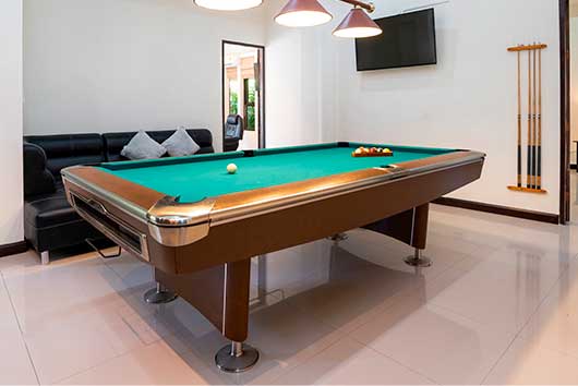 A stylish living area with a pool table, couch, and sliding glass door, emphasizing a contemporary recreational environment.