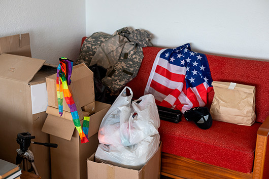 A red couch surrounded by boxes and a camera, depicting a scene related to moving in Southern California military bases.