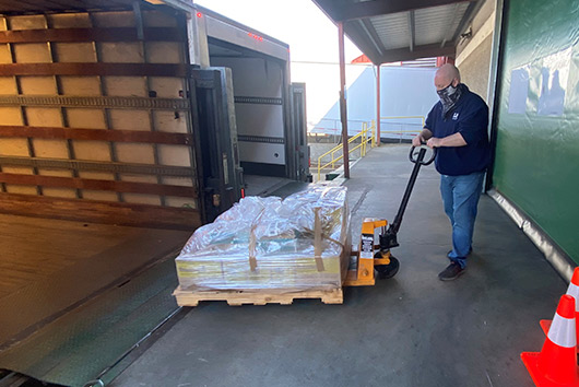 A man loads pallets onto a truck in a busy storage area, showcasing efficient logistics in San Marcos.