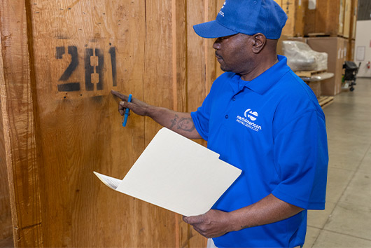 A man wearing a blue shirt is holding a clipboard, possibly working on the San Marcos Business Storage Guide.
