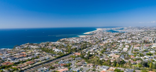 Aerial drone shot over Newport Beach in Orange County, California with coastal neighborhoods on blue sky sunny day.