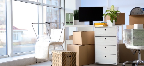 Cardboard boxes and packed belongings in office. Moving day