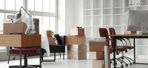 Workplaces with cardboard boxes in office on moving day