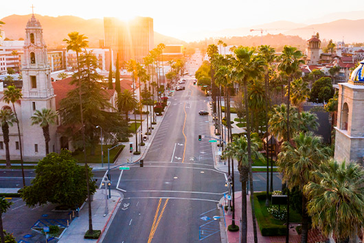 A vibrant street adorned with palm trees and a clock tower, illustrating the Inland Empire guide for corporate office relocation.