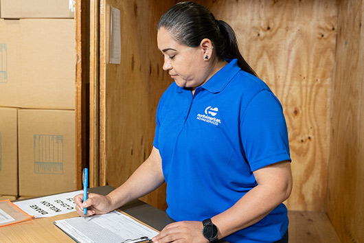 A woman wearing a blue shirt is diligently working on a document, connected to Long-Term Storage Solutions in San Marcos.