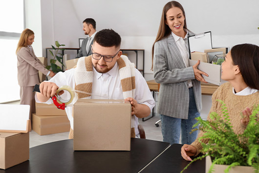 Several individuals transporting boxes in an office, part of a government relocation in San Diego.