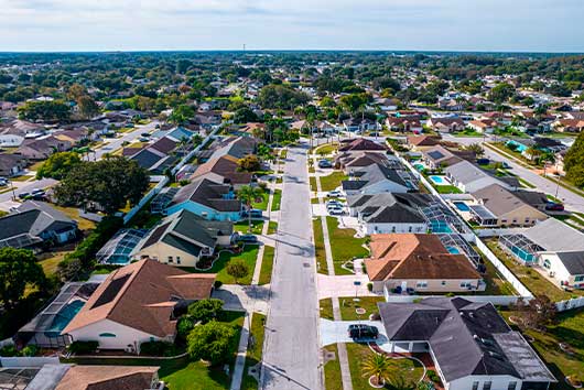 Aerial perspective of a suburban area, featuring houses and greenery, representing a transition from San Diego to Orlando.