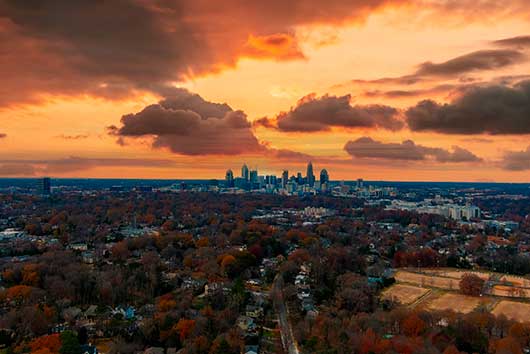 Overhead perspective of a city skyline during an autumn sunset, highlighting warm hues and the transition to evening.